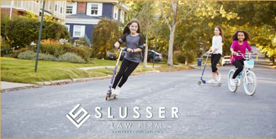 3 Children on Scooters and Bikes Playing in the Street