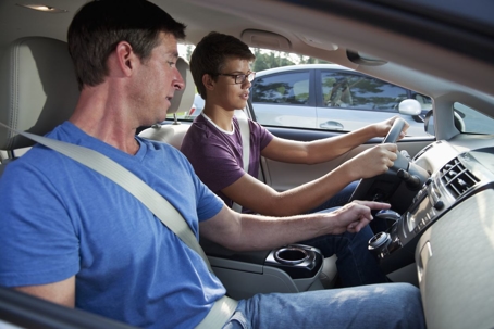 Father instructing young teen driver