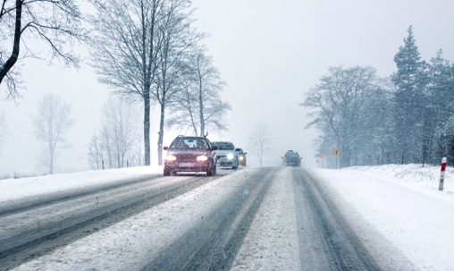Cars in a wooded area driving on snowy roads
